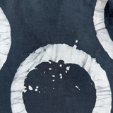 Black ink splatter on a white circular object against a dark background